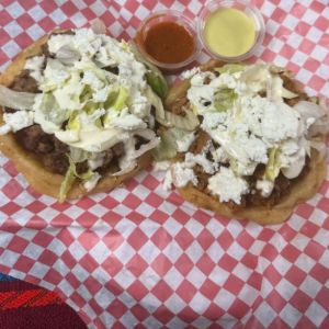 Two sopes with meat, lettuce and white cheese, with two salsas